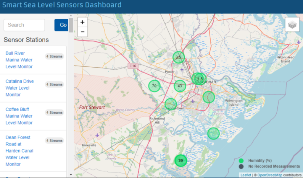 A screenshot of the Smart Sea Level Sensors dashboard, an interactive map with real-time water level data from the sea level sensors in Chatham county. Prominent in the screenshot is a view of Chatham county, with a number of circles scattered around the area representing the sea level sensors. On the side, the names of several sensor stations are listed; clicking these names opens a more detailed report of their real-time data.
